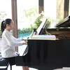 Trần Minh Châu bên cây đàn piano. (Ảnh: Nguyễn Văn Cảnh/TTXVN)