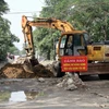 Chính quyền phường Vinh Tân huy động máy móc để san phẳng gạch đá, đảm bảo giao thông thông suốt trên đường Phạm Hồng Thái. (Ảnh: Tá Chuyên/TTXVN)