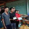 Chủ tịch Hội người Việt Nam tại tỉnh Attapeu Võ Văn Mừng trao tặng số tiền 1 triệu Kip cho 3 gia đình bị ảnh hưởng sau sự cố vỡ đập thủy điện. (Ảnh: Quang Thái/TTXVN)