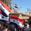 Người dân Syria giương cao quốc kỳ sau khi quân đội giành quyền kiểm soát tỉnh Daraa từ lực lượng nổi dậy ngày 12/7. (Nguồn: AFP/TTXVN)
