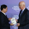 Giáo sư Klaus Schwab, Người sáng lập, Chủ tịch Điều hành Diễn đàn Kinh tế thế giới (bên phải) trao sách tặng Thứ trưởng Thường trực Bộ Ngoại giao Bùi Thanh Sơn. (Ảnh: Lâm Khánh/TTXVN)