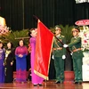 Chủ tịch Quốc hội Nguyễn Thị Kim Ngân gắn huy hiệu Anh hùng Lực lượng vũ trang nhân dân lên lá cờ truyền thống của Ban Dân y Trung ương cục miền Nam. (Ảnh: Trọng Đức/TTXVN)