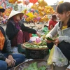 Cô gái trẻ Trần Thị Phúc (bên trái) tươi cười bán trầu cau cho khách. Đây là năm thứ hai cô bán trầu cau ở hội chợ Gò. (Ảnh: Quốc Dũng/TTXVN)