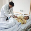Bà Nguyễn Thị Như T được bác sĩ kiểm tra tình hình sức khỏe trước khi xuất viện. (Ảnh: Lê Xuân/TTXVN)