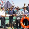 Cán bộ Bộ Tư lệnh Vùng 2 Hải quân tặng cờ Tổ quốc và phao cứu sinh cho ngư dân. (Ảnh: Huỳnh Ngọc Sơn/TTXVN)