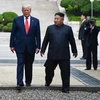 Tổng thống Mỹ Donald Trump (trái) và nhà lãnh đạo Triều Tiên Kim Jong-un bước chân qua đường ranh giới phân chia hai miền Triều Tiên tại DMZ, sang phần lãnh thổ của Triều Tiên chiều 30/6/2019. (Nguồn: AFP/TTXVN)