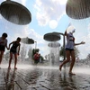 Trẻ em chơi đùa dưới vòi phun nước để tránh nắng nóng tại Vilnius, Lítva, ngày 13/6/2019. (Nguồn: AFP/TTXVN)