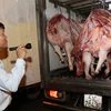 Kiểm tra thịt lợn trước khi được đưa đi tiêu thụ tại chợ đầu mối nông sản thực phẩm Hóc Môn, Thành phố Hồ Chí Minh. (Ảnh: Đinh Hằng/TTXVN)