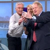 Hình ảnh Thủ tướng Johnson dùng điện thoại Huawei chụp ảnh tự sướng kỷ niệm với hai người dẫn chương trình. (Nguồn: https://twitter.com/johnestevens)