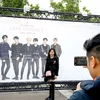 Một phụ nữ chụp ảnh phía trước tấm poster hình ảnh nhóm nhạc BTS bên ngoài sân vận động Stade-de-France, Paris, Pháp. (Nguồn: AFP)