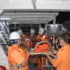 Thuyền viên tàu cứu nạn chuyên dụng SAR 413 đưa thuyền viên Khu Văn Khoan từ tàu SAR 413 lên bờ. (Nguồn: TTXVN phát)