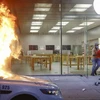 Một người chạy khỏi Apple Store tại Philadelphia trong khi một chiếc xe cảnh sát đỗ phía trước cửa hàng bị đốt cháy, ngày 30/5/2020. (Nguồn: AP)