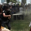Cô gái mặc váy đỏ bị cảnh sát xịt hơi cay vào mặt. (Nguồn: Reuters)