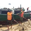 Cán bộ, chiến sĩ bộ đội biên phòng cùng nhân dân địa phương hỗ trợ giải cứu tàu cá gặp nạn. (Ảnh: Võ Dung/TTXVN)