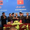 Bộ trưởng Bộ Công Thương Việt Nam Vũ Huy Hoàng và Bộ trưởng Bộ Công Thương Lào Khemmani Pholsena ký Hiệp định. (Ảnh: Tá Chuyên/TTXVN)