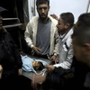 Người thân bên thi thể một nạn nhân trong vụ oanh tạc của Israel tại Dải Gaza ngày 24/12. (Nguồn: AFP/TTXVN)