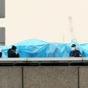 Cảnh sát kiểm tra vật thể bay được phát hiện trên nóc Văn phòng Thủ tướng Nhật. (Ảnh: AFP/TTXVN phát)