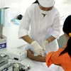 Cán bộ y tế của Trung tâm phòng chống HIV/AIDS tỉnh Ninh Bình lấy mẫu máu xét nghiệm HIV/AIDS cho khách hàng. (Ảnh: Dương Ngọc/TTXVN)
