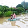 Nhiều phương tiện tự chế được sủ dụng để đi qua vùng nước ngập lụt tại dốc đèo Bụt, phường Hà Phon. (Ảnh: Minh Quyết/TTXVN)