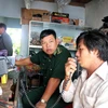 Người nhà anh Võ Văn Hưng theo dõi thông tin qua máy bộ đàm. (Ảnh : Đoàn Mạnh Dương/TTXVN)