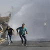 Người Palestine chạy trốn vòi rồng do cảnh sát Israel sử dụng trong xung đột tại Thánh đường al-Aqsa ở Jalazoun, gần thành phố Ramallah ngày 18/9. (Nguồn: Reuter/TTXVN)