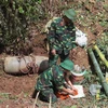 Các chiến sỹ công binh lắp đặt khối thuốc nổ để hủy nổ một quả bom ở Sơn La. (Ảnh: Lê Hữu Quyết/TTXVN)