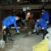 Sinh viên tình nguyện trộn vật liệu xây dựng chuẩn bị lát nền nhà cho các hộ dân có hoàn cảnh khó khăn. (Ảnh: Phạm Kiên/TTXVN)