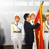 Phó Thủ tướng Vũ Đức Đam gắn Huân chương Hồ Chí Minh lên lá cờ truyền thống của Trường Đại học Mỹ thuật Việt Nam. (Ảnh: Minh Đức/TTXVN)