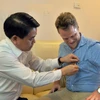 Chủ tịch Nguyễn Đức Chung đã tặng và tự tay gắn lên ngực áo anh James Joseph Kendall logo của thành phố Hà Nội. (Ảnh: /Vietnam+)