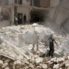 Lực lượng cứu hộ tìm kiếm người mắc kẹt trong đống đổ nát sau cuộc giao tranh ở Aleppo ngày 20/6. (Nguồn: AFP/TTXVN)