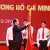 Chủ tịch nước Trần Đại Quang gắn Huân chương Hồ Chí Minh lên Cờ truyền thống của Trường Đại học Bách Khoa Hà Nội. (Ảnh: Quý Trung/TTXVN)