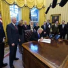 Tổng thống Mỹ Donald Trump (ngồi, trái) ký sắc lệnh hành pháp cấm tạm thời người tị nạn vào Mỹ, tại Nhà Trắng ngày 28/1. (Nguồn: AFP/TTXVN)