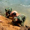 Lực lượng công binh thuộc Bộ Chỉ huy Quân sự tỉnh Phú Yên di chuyển quả bom từ bờ sông lên bờ để xử lý hủy nổ. (Ảnh: Thế Lập/TTXVN)