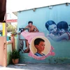 Một bức tranh trên tường nhà vẽ về một gia đình trong làng là người đàn ông làm nghề may cùng vợ và hai con nhỏ tại làng bích họa. (Ảnh: Trần Lê Lâm/TTXVN)