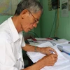 Cựu chiến binh Đào Thiện Sính viết thư cho thân nhân liệt sỹ. (Ảnh: Phan Sáu/TTXVN)