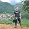 Nhà báo Đinh Hữu Dư trên đường tác nghiệp (Ảnh: Nội san TTXVN)