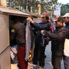 Người dân lao động đến lấy quần áo mặc chống rét tại quầy hàng miễn phí trên phố Nguyễn Chí Thanh. (Ảnh: Thành Đạt/TTXVN)