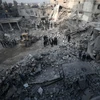 Tìm kiếm các nạn nhân sau một vụ không kích xuống Hamouria, Đông Ghouta ngày 9/1. (Nguồn: AFP/TTXVN)