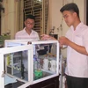 Em Giang Quốc Hoàn và Đỗ Hữu Toàn kiểm tra mô hình robot thí nghiệm hóa học. (Ảnh: Thùy Dung/TTXVN)