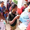 Người dân tại trung tâm huyện Sanamxay tiếp nhận hàng cứu trợ. (Ảnh: Quang Thái/TTXVN)