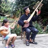 Nghệ nhân Dương Văn Thục truyền dạy cách đàn tính, hát then cho người cháu của mình. (Ảnh: Đức Hiếu/TTXVN)