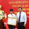 Phó chủ tịch UBND tỉnh Quảng Ngãi Nguyễn Tăng Bính trao Huân chương Dũng cảm cho ngư dân Trần Thanh Ron. (Ảnh: Phước Ngọc/TTXVN)