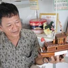 Ông Nguyễn Văn Léo bên sản phẩm tàu biển. (Ảnh: Huỳnh Phúc Hậu/TTXVN)