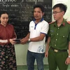 Anh Phan Lâm Nhuận (thứ hai từ phải qua) trao trả túi xách cho chị Nguyễn Thị Cẩm Tú trước sự chứng kiến của công an. (Ảnh: Nguyễn Văn Việt/TTXVN)