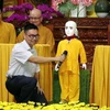 Tiến sỹ, kỹ sư Nguyễn Bá Hải hướng dẫn người dân đặt câu hỏi về Phật pháp cho chú tiểu Giác Ngộ 4.0. (Ảnh: Xuân Khu/TTXVN)