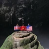 Khách du lịch khám phá hang động chụp ảnh cùng với 3 lá quốc kỳ Mỹ-Triều Tiên-Việt Nam tại hang Én, tỉnh Quảng Bình. (Ảnh: TTXVN phát)