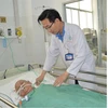 Bác sỹ thăm khám Bà mẹ Việt Nam anh hùng Đinh Thị Thà sau phẫu thuật. (Ảnh: TTXVN phát)
