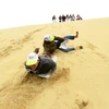 Du khách thích thú tham gia trò chơi trượt cát. (Ảnh: Mạnh Thành/TTXVN)