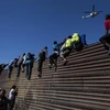 Người di cư trèo qua hàng rào ngăn cách biên giới Mỹ - Mexico gần cửa khẩu El Chaparral ở Tijuana, bang Baja California, Mexico, ngày 25/11/2018. (Ảnh: AFP/ TTXVN)