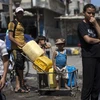 Trẻ em Palestine xếp hàng lấy nước sinh hoạt tại thành phố Gaza. (Ảnh: AFP/TTXVN)